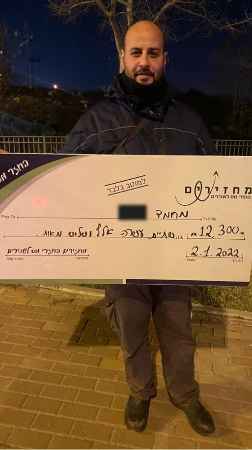 החזר מס ללקוחות שלנו - מחמד מחזיק צ'ק כספי שקיבל 12,300 שח בהחזר מס לקוח שלנו והצטלם לאחר קבלת הכסף